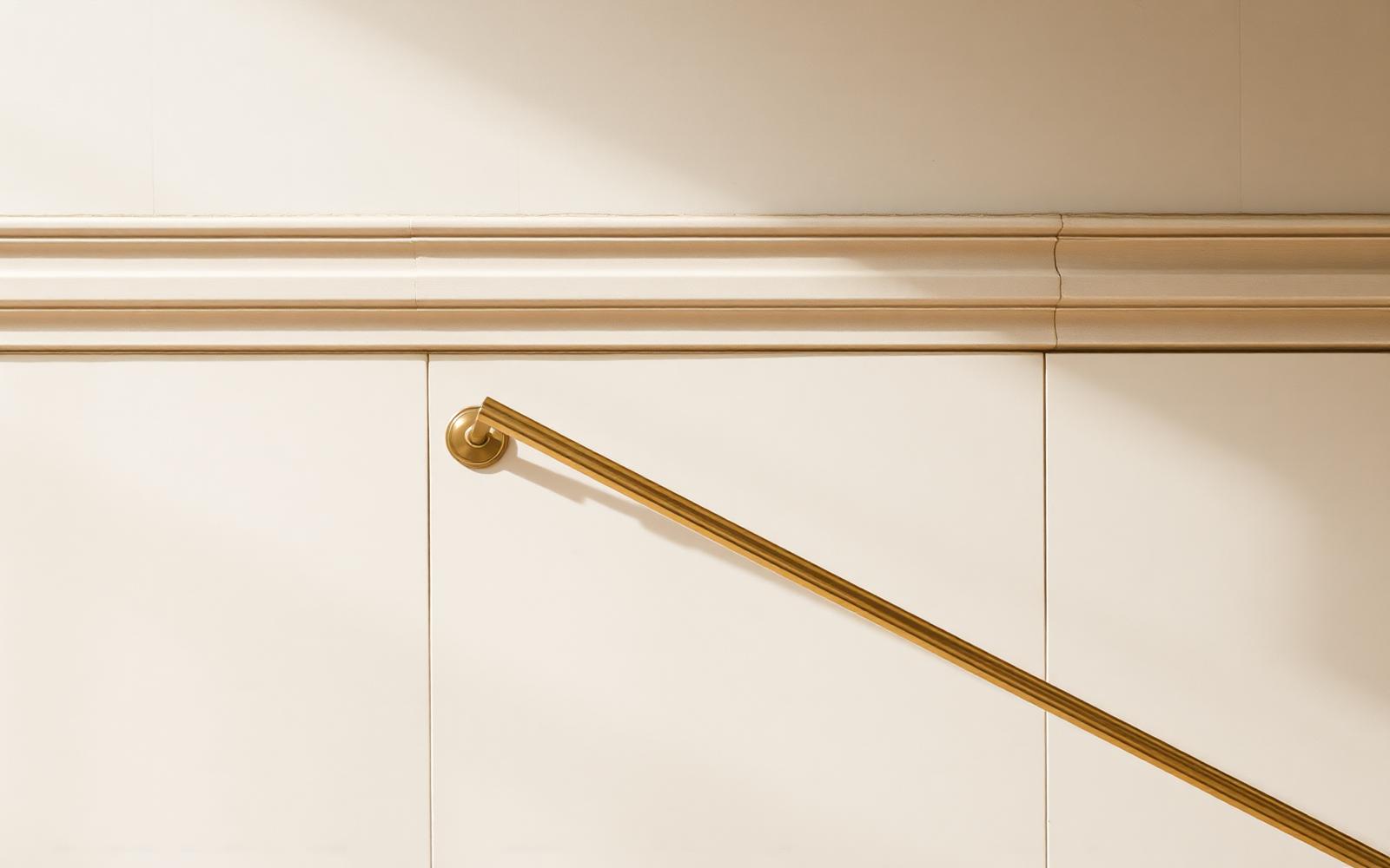 Quiet bronze handrail against pale limestone